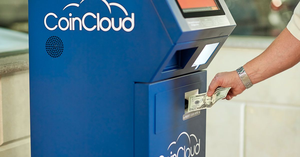 A person using a CoinCloud Bitcoin ATM to insert cash for cryptocurrency transactions.
